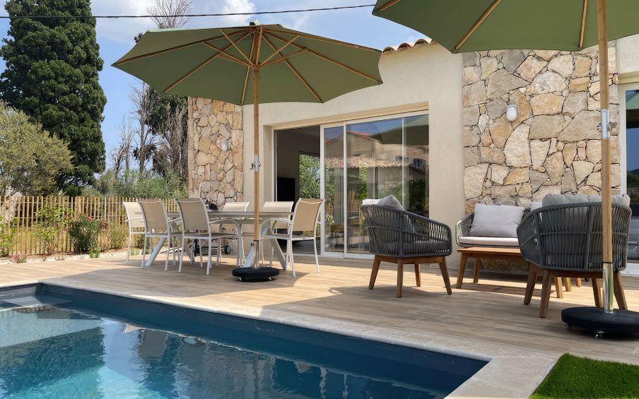 Grande terrasse et sa piscine avec une vue à couper le souffle sur la baie de Calvi. La terrasse offre des bains de soleil, une table à manger, un salon de jardin. Une vraie continuité avec la pièce de vie de la villa.
