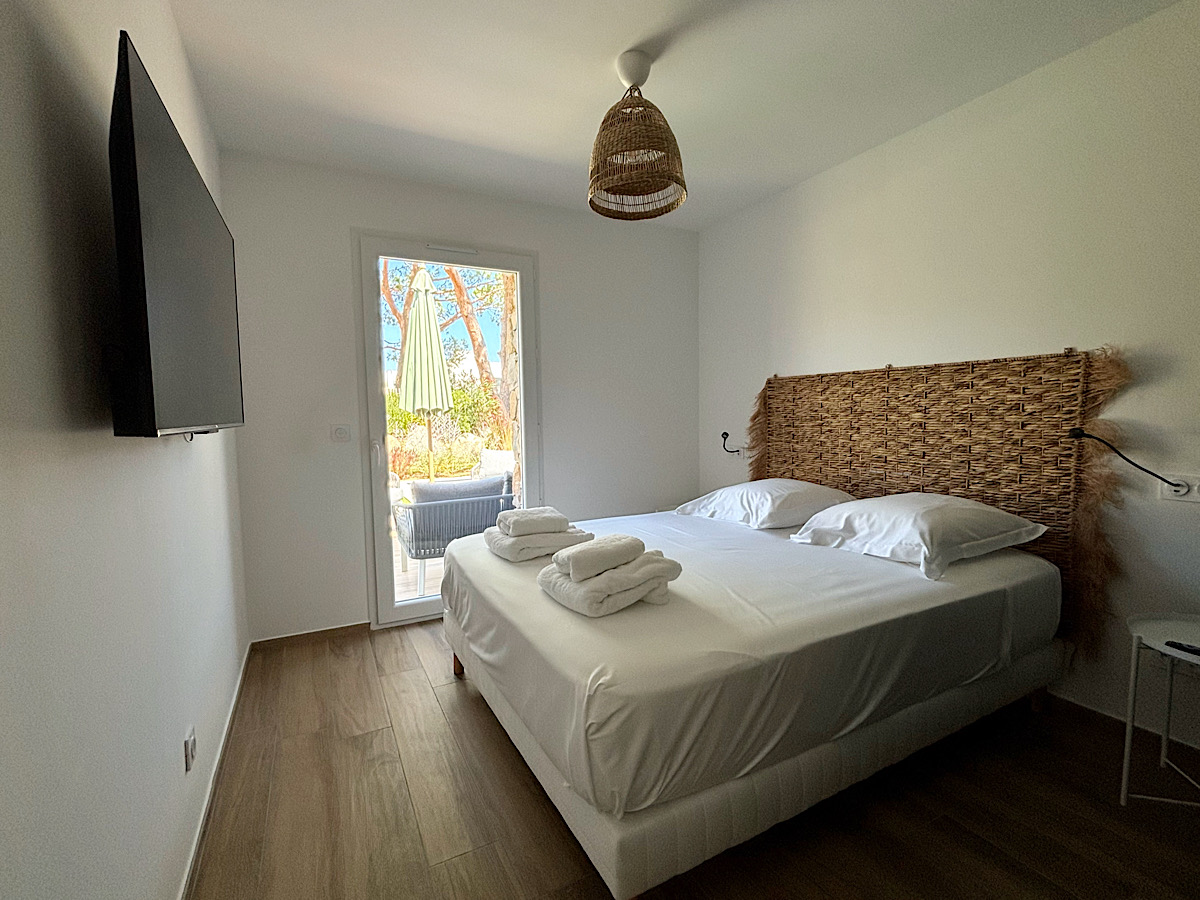Chambre équipée d'un lit double 160 avec tables de chevet, lampes de lecture, grand placard de rangement et un accès à son balcon. La chambre offre également une vue complète sur la baie de Calvi.