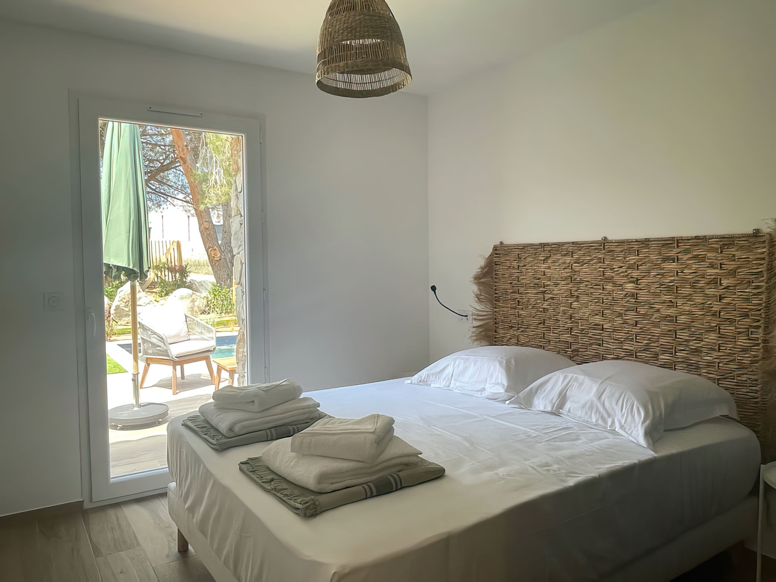 Chambre équipée d'un lit double 160 avec tables de chevet, lampes de lecture, grand placard de rangement et un accès à son balcon. La chambre offre également une vue complète sur la baie de Calvi.