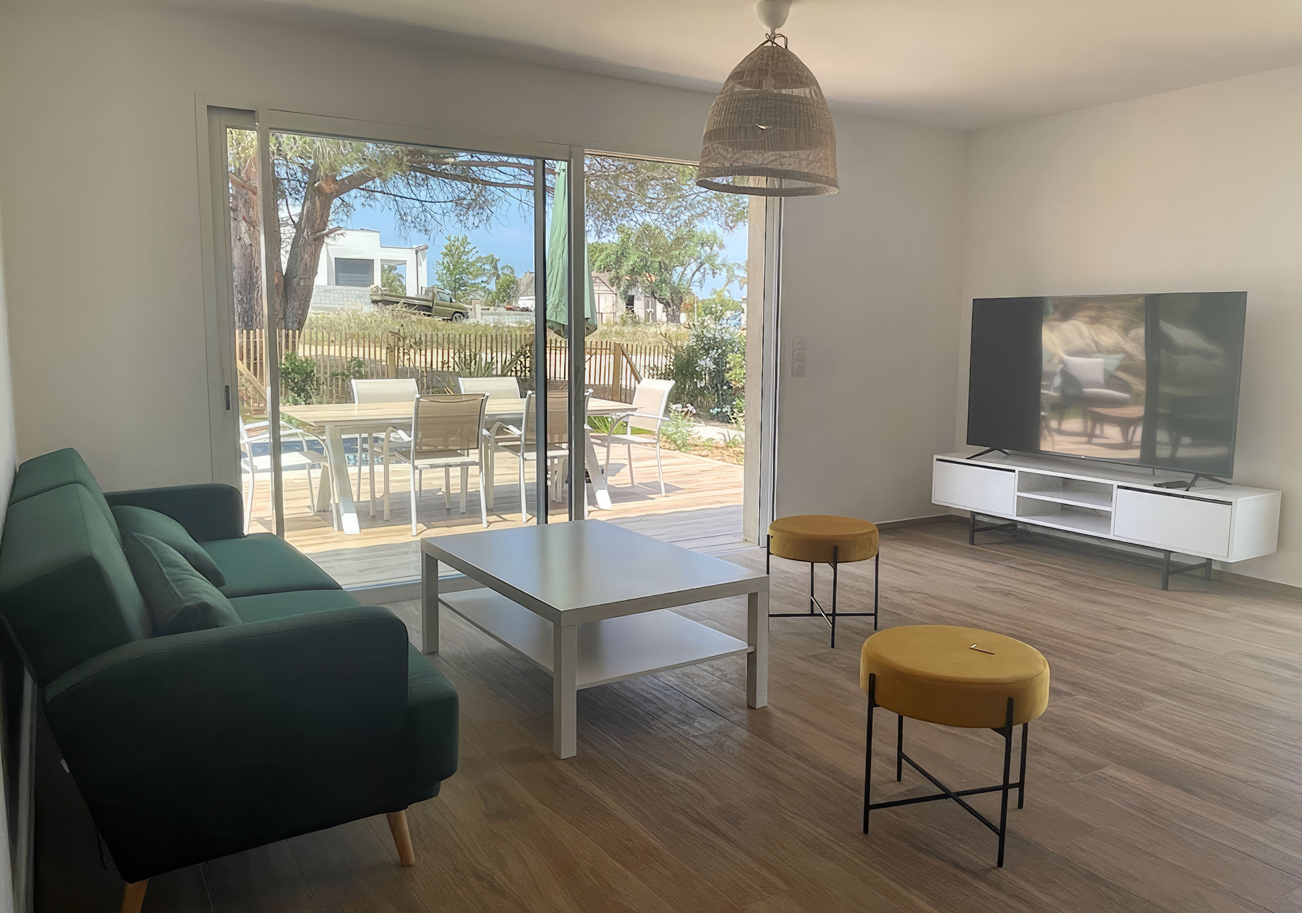 Salon moderne équipé d'un canapé de chez Cuir center 6 assises, d'un télévision murale connectée. Le salon offre une vue complète sur la terrasse piscine et la baie de Calvi