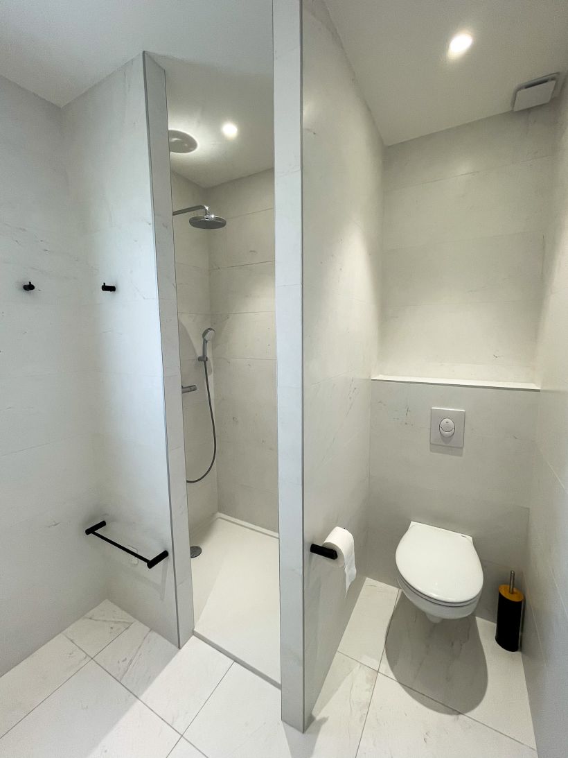 Grande douche italienne entièrement carrelée aspect marbre et son WC privatif