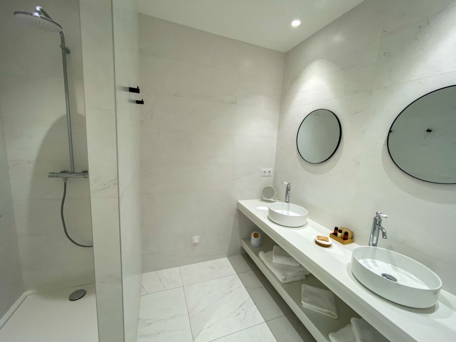 Salle de bains avec double vasque et douche à l'italienne. Salle de bains entièrement carrelée effet marbre noir et blanc